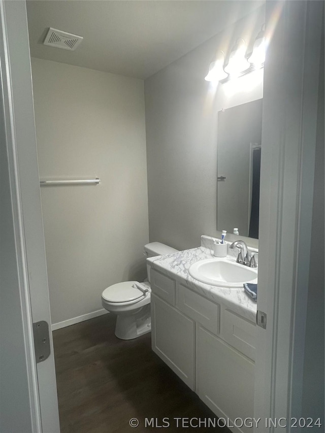 bathroom with hardwood / wood-style flooring, vanity, and toilet