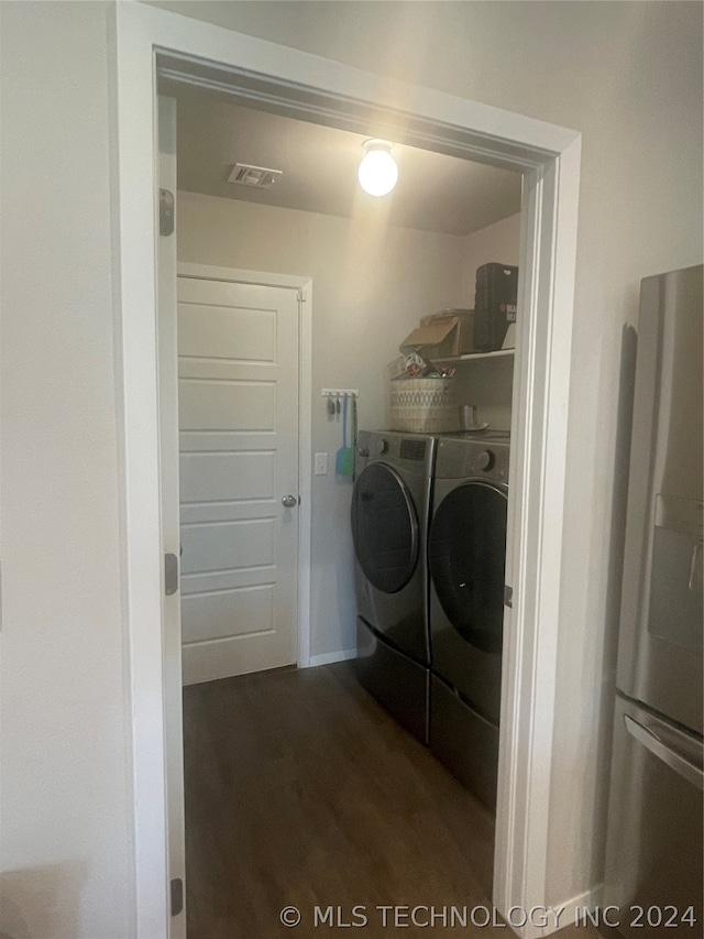 clothes washing area featuring washer and clothes dryer and dark hardwood / wood-style floors