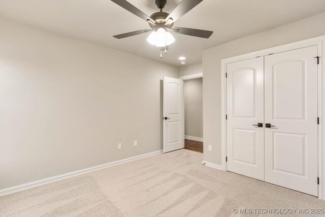 unfurnished bedroom featuring ceiling fan, light colored carpet, and a closet