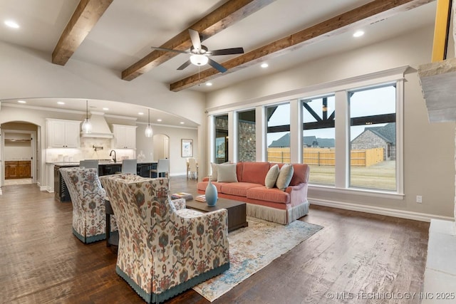 living room with sink, ornamental molding, ceiling fan, dark wood-type flooring, and beam ceiling