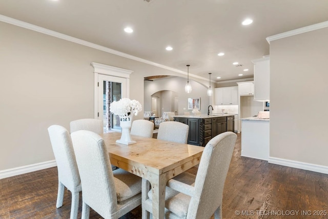 dining area with crown molding, sink, and dark hardwood / wood-style flooring