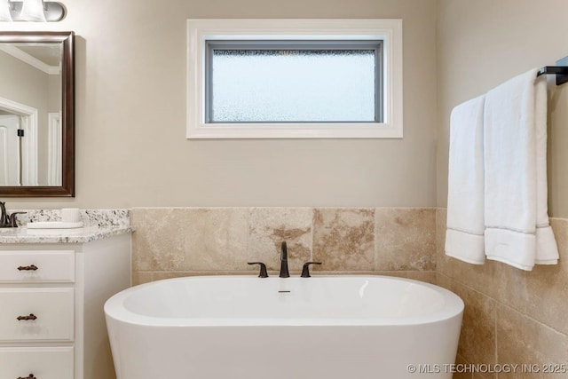 bathroom with vanity, a bathtub, and tile walls