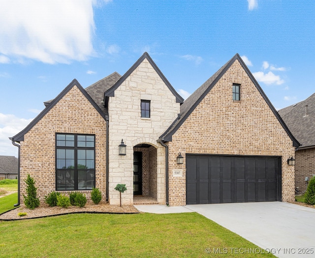 french country inspired facade featuring driveway, a front lawn, an attached garage, roof with shingles, and brick siding