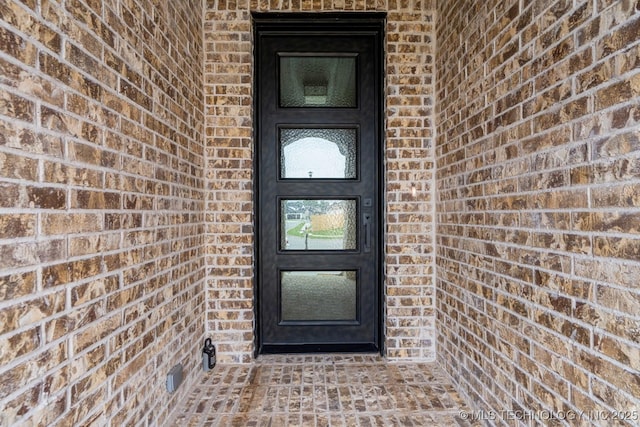 entrance to property featuring brick siding