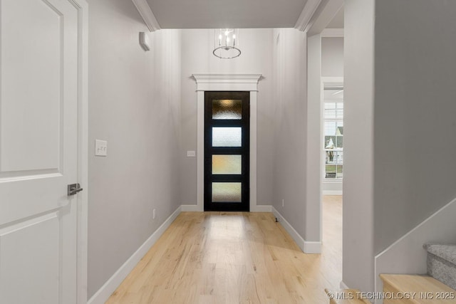 entryway featuring light wood finished floors, baseboards, and stairway