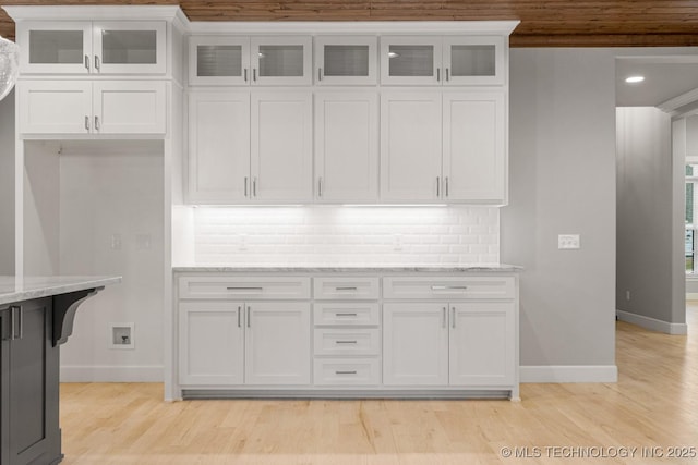 kitchen featuring baseboards, white cabinets, light stone countertops, tasteful backsplash, and recessed lighting