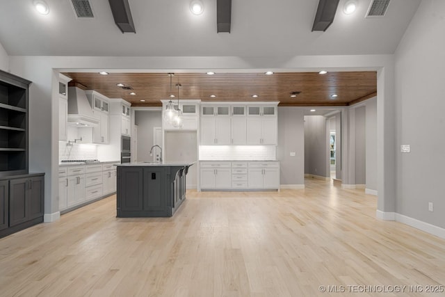 kitchen with wall chimney range hood, light wood-type flooring, backsplash, recessed lighting, and wood ceiling