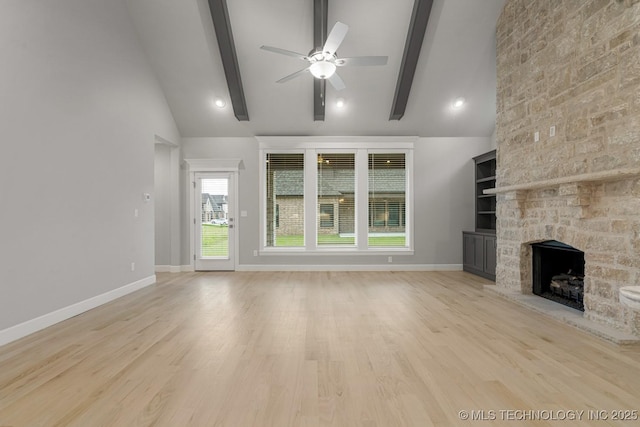 unfurnished living room featuring a ceiling fan, beam ceiling, a fireplace, baseboards, and light wood-style floors