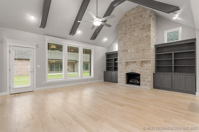 unfurnished living room featuring ceiling fan, light wood-style floors, a fireplace, high vaulted ceiling, and beam ceiling