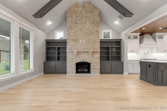 unfurnished living room with light wood-style flooring, healthy amount of natural light, high vaulted ceiling, recessed lighting, and beam ceiling