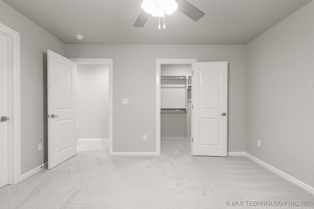 unfurnished bedroom with light carpet, baseboards, and a walk in closet