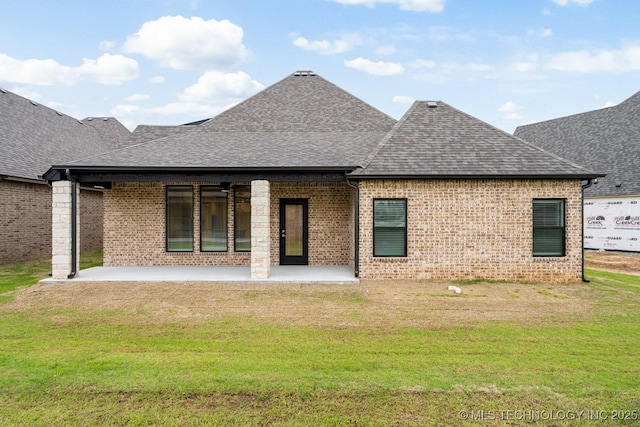 rear view of property featuring a shingled roof, a yard, a patio, brick siding, and a ceiling fan