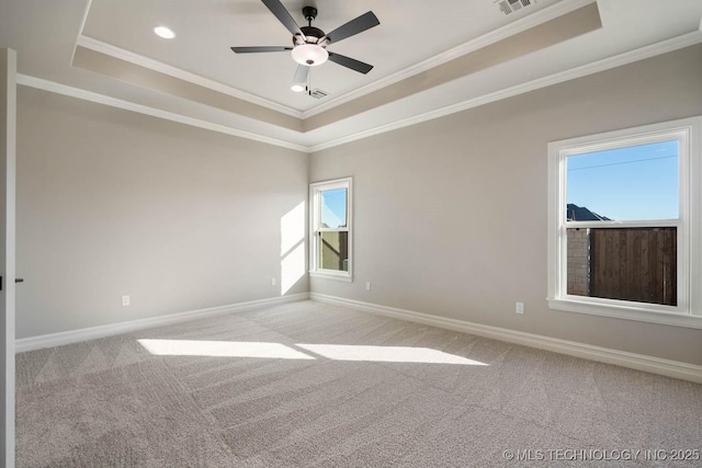 carpeted spare room with ceiling fan, a tray ceiling, and crown molding