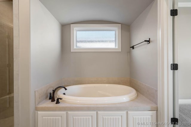 bathroom featuring vaulted ceiling and a bath