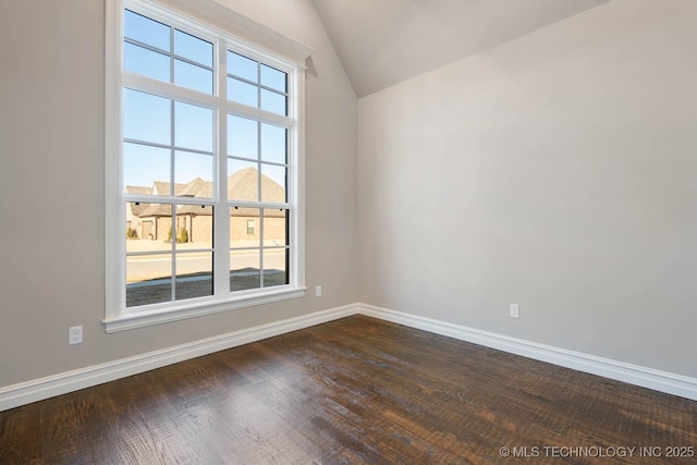 spare room with vaulted ceiling, dark wood-type flooring, and a healthy amount of sunlight