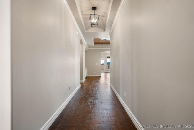 corridor featuring crown molding, dark hardwood / wood-style floors, and a notable chandelier