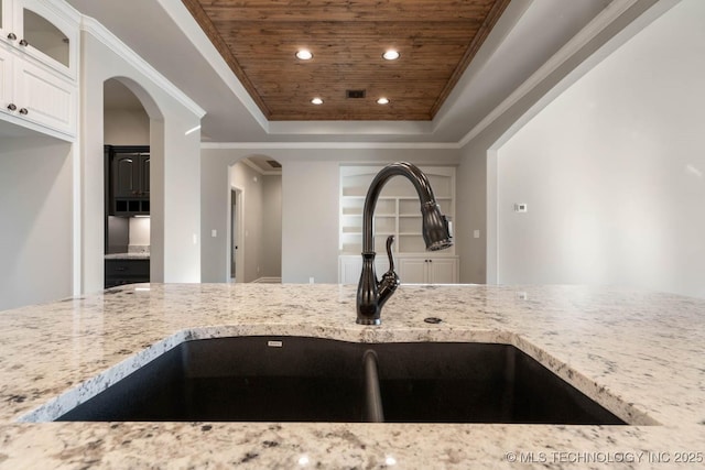 kitchen with white cabinetry, sink, a raised ceiling, light stone counters, and wooden ceiling