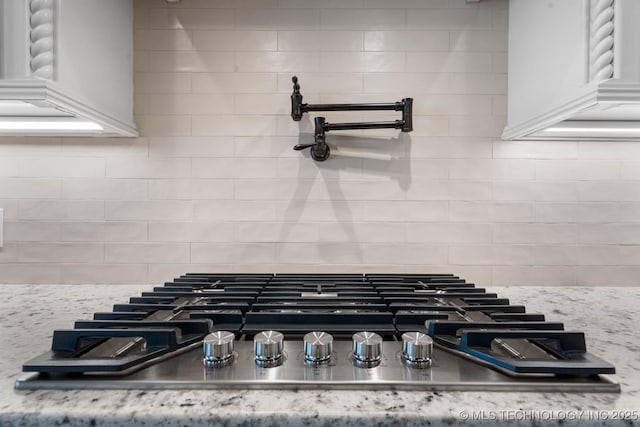 details with light stone counters, stainless steel gas cooktop, and tasteful backsplash