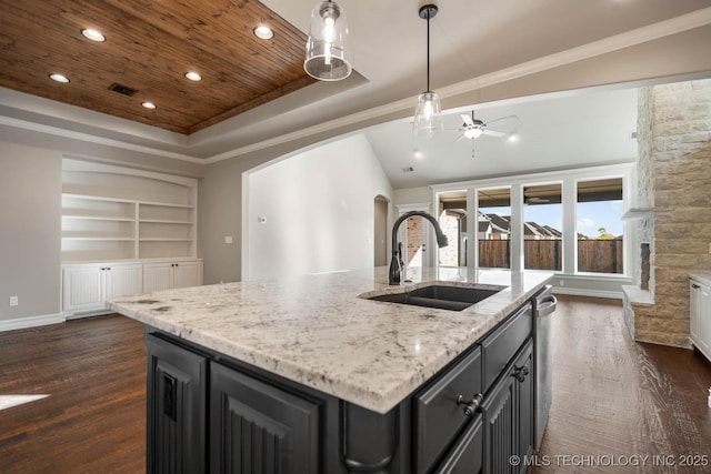 kitchen with ceiling fan, dark hardwood / wood-style floors, sink, built in features, and an island with sink