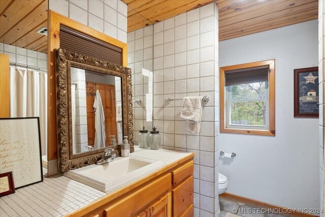 9212 N 447th Rd, Spavinaw, OK 74366 - full bath featuring tile walls, toilet, wood ceiling, vanity, and baseboards