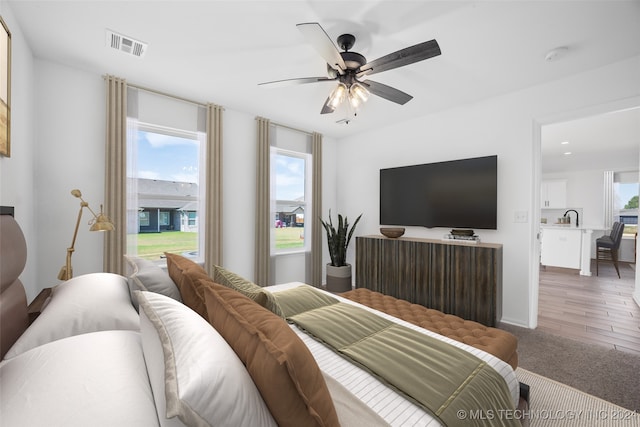 bedroom featuring wood-type flooring, sink, and ceiling fan