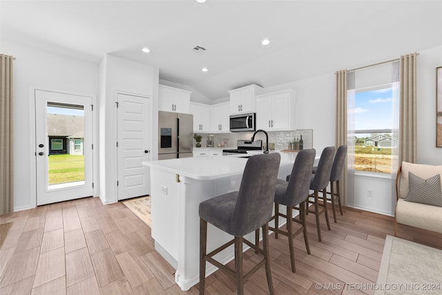 kitchen featuring white cabinets, kitchen peninsula, light hardwood / wood-style flooring, appliances with stainless steel finishes, and a kitchen bar