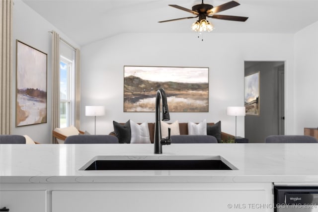 interior space with light stone countertops, vaulted ceiling, sink, and white cabinets