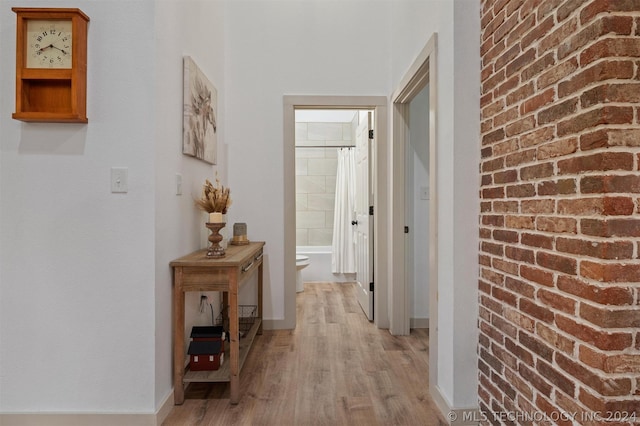 corridor featuring brick wall and hardwood / wood-style flooring