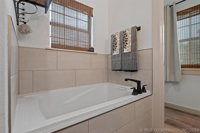 bathroom featuring tiled bath and hardwood / wood-style floors