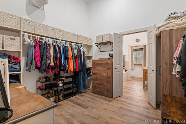 walk in closet with light hardwood / wood-style floors and a towering ceiling