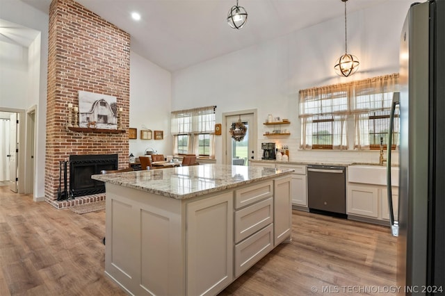 kitchen featuring stainless steel appliances, white cabinets, a fireplace, light hardwood / wood-style floors, and brick wall