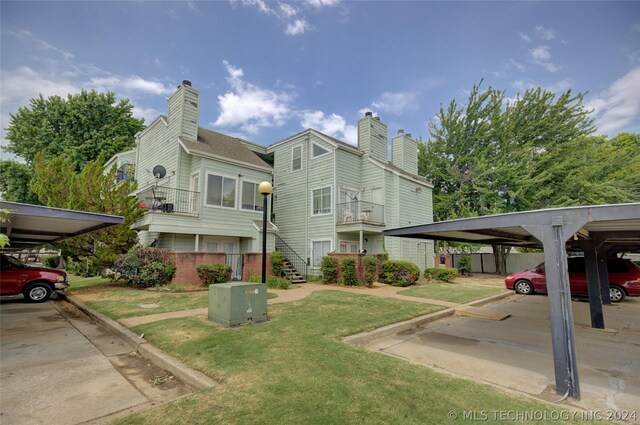 exterior space with a balcony, a lawn, and a carport