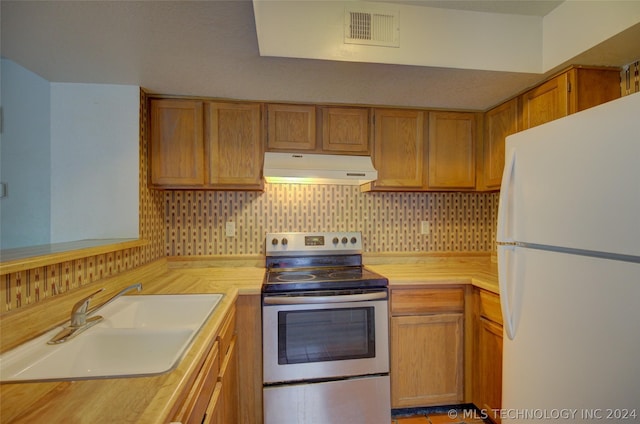 kitchen with sink, white refrigerator, extractor fan, decorative backsplash, and stainless steel range with electric cooktop