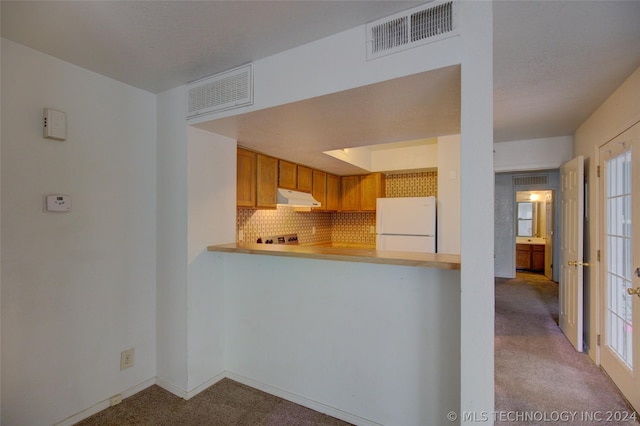 kitchen with white refrigerator, light carpet, decorative backsplash, and kitchen peninsula