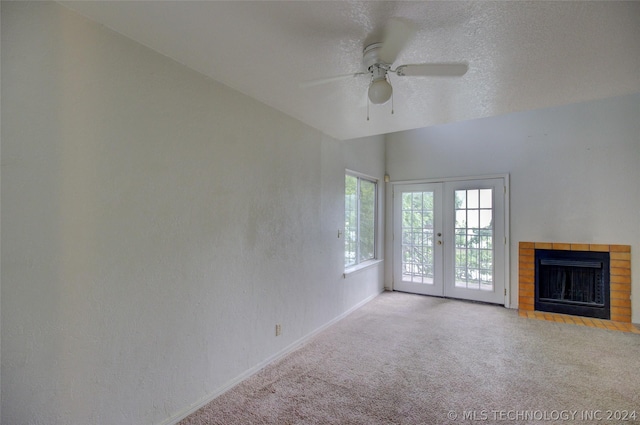 unfurnished living room featuring ceiling fan, light colored carpet, a textured ceiling, and french doors