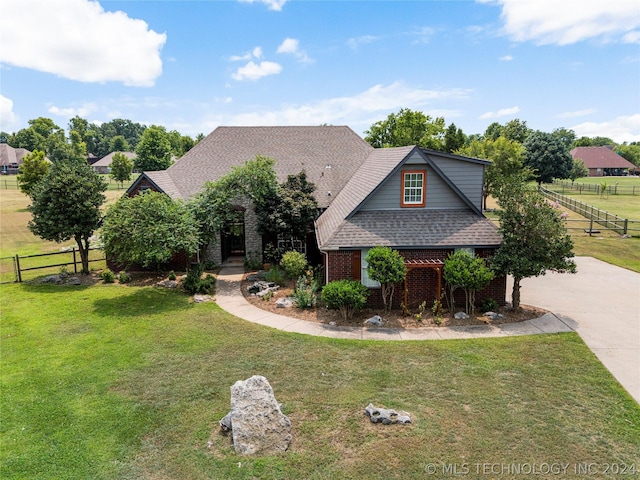 craftsman-style home with brick siding, fence, driveway, roof with shingles, and a front lawn