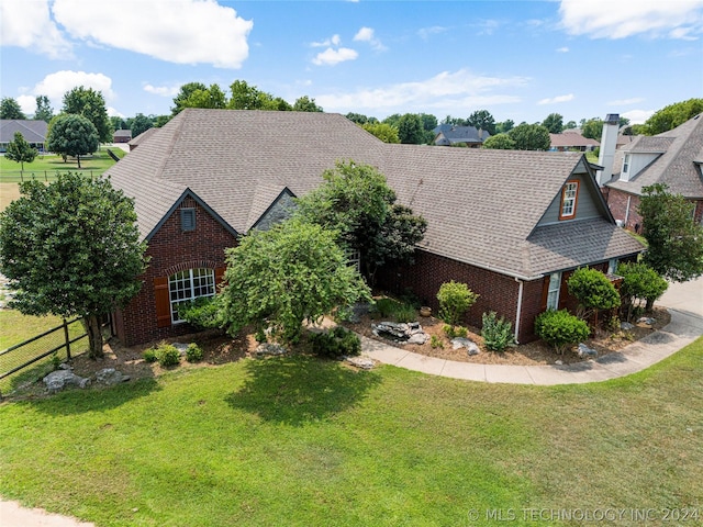 view of front of property with brick siding, fence, a front lawn, and roof with shingles