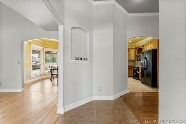 hall with light tile patterned floors, crown molding, and arched walkways