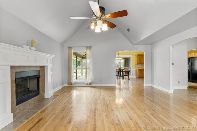 unfurnished living room featuring a tile fireplace, high vaulted ceiling, light wood-type flooring, and ceiling fan