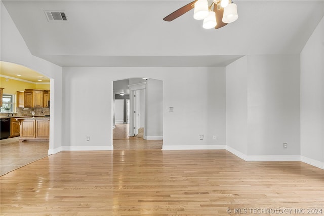 unfurnished living room with arched walkways, light wood-style flooring, ceiling fan, baseboards, and visible vents