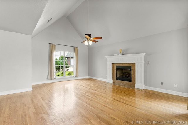 unfurnished living room with light wood finished floors, a fireplace, high vaulted ceiling, a ceiling fan, and baseboards