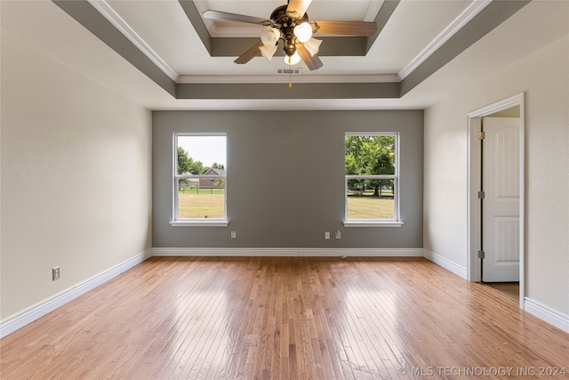 spare room with a raised ceiling, crown molding, light wood-type flooring, and ceiling fan