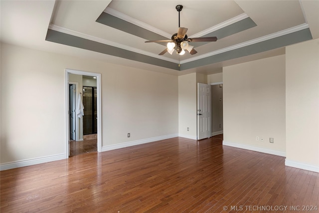 unfurnished room with wood finished floors, baseboards, a ceiling fan, crown molding, and a tray ceiling