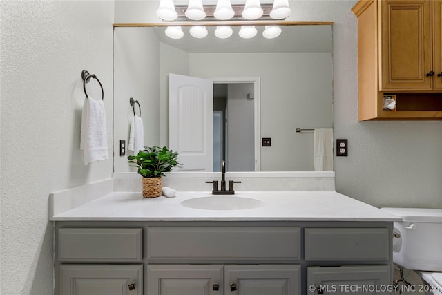 bathroom with toilet, a textured wall, and vanity
