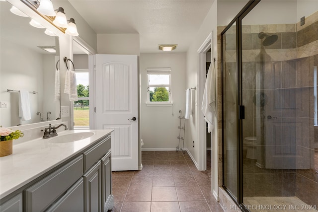 bathroom featuring a shower with shower door, vanity, tile patterned floors, and toilet