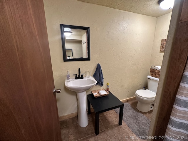 bathroom featuring a textured ceiling, tile patterned floors, and toilet