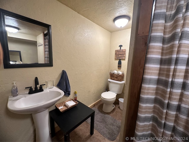 bathroom with tile patterned flooring, a textured ceiling, curtained shower, and toilet