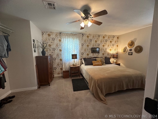 bedroom with ceiling fan, carpet floors, and a textured ceiling