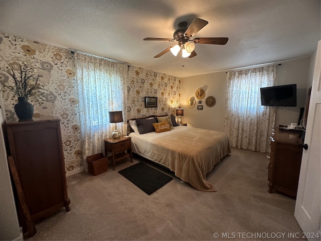 carpeted bedroom featuring ceiling fan and a textured ceiling