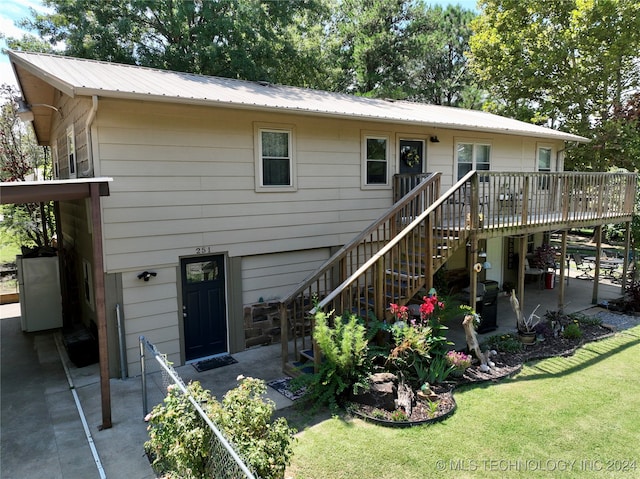 view of front of house with a wooden deck, a patio, and a front yard